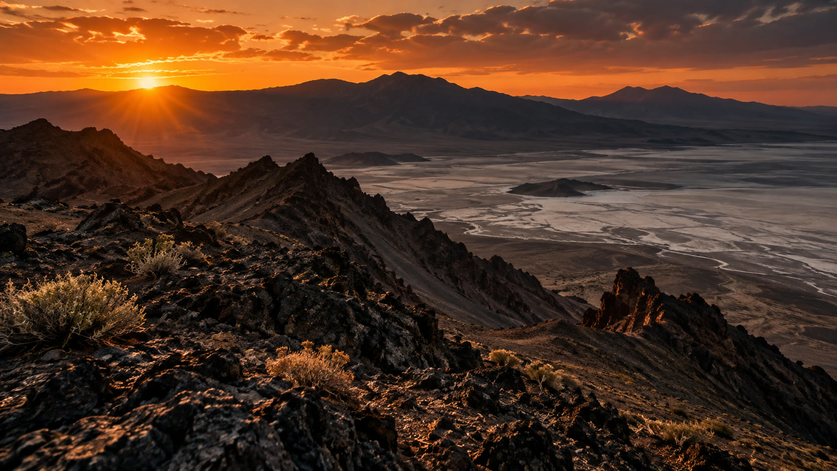 Sunset over dark mountain ridges and a cloud-filled valley