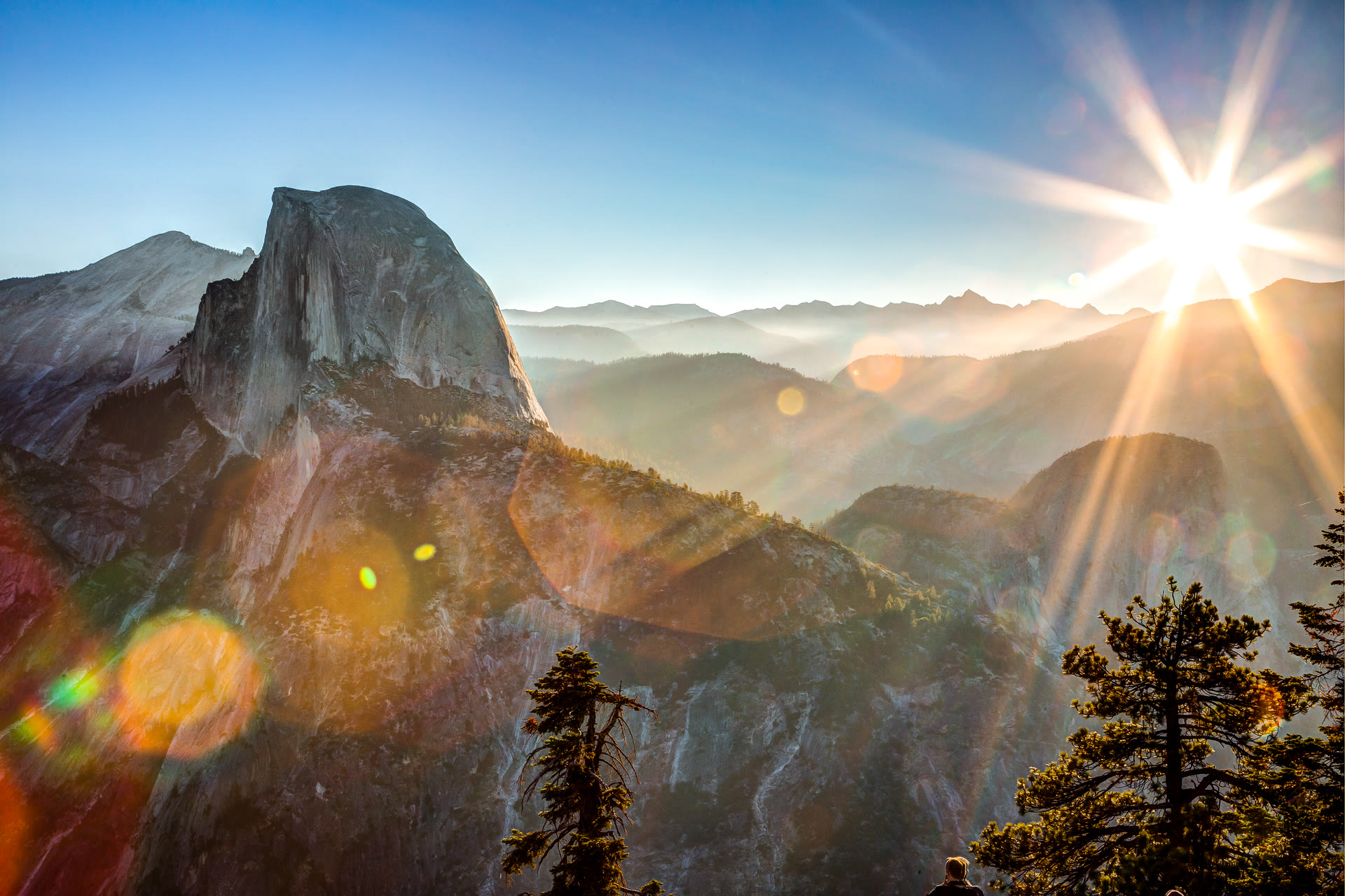Sunrise illuminating granite cliffs and a forested mountain valley